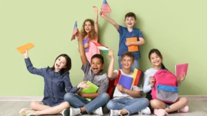 Children sitting on the floor with backpacks, ready for school, holding flags representing different countries, symbolizing their international backgrounds.
